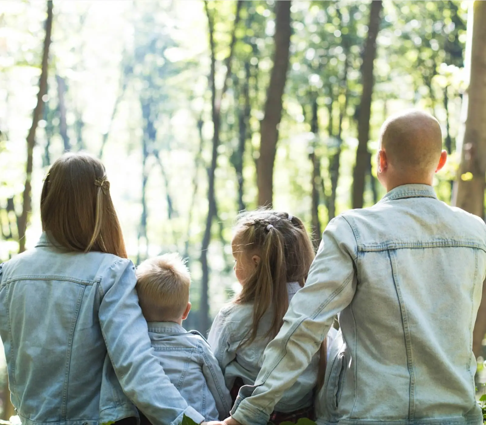 a family close together looking towards a forest holding hands