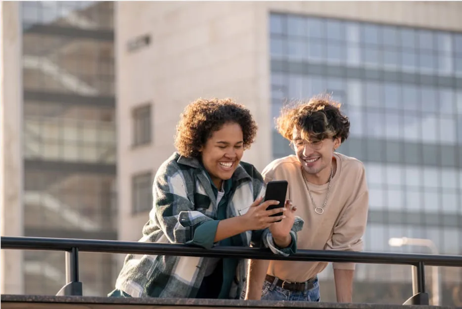 2 people laughing together looking at something on a phone