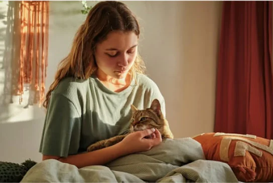 a young girl sitting with her cat on her lap