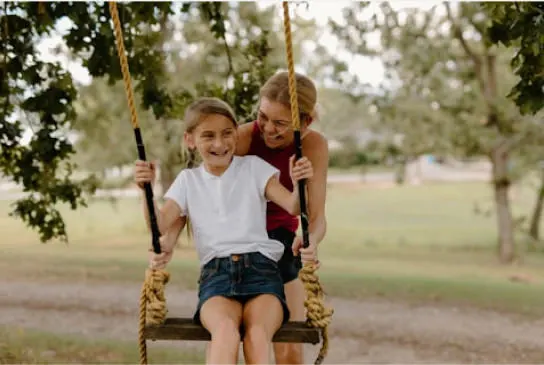 a mother and daughter playing on a swing