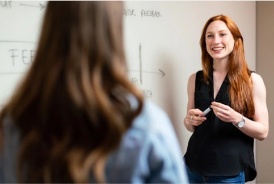 a woman standing in front of another woman teaching