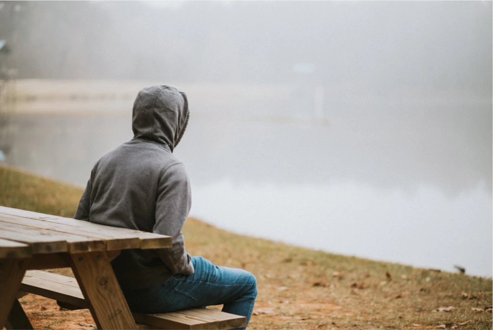 a person looking out to a body of water sitting on a bench