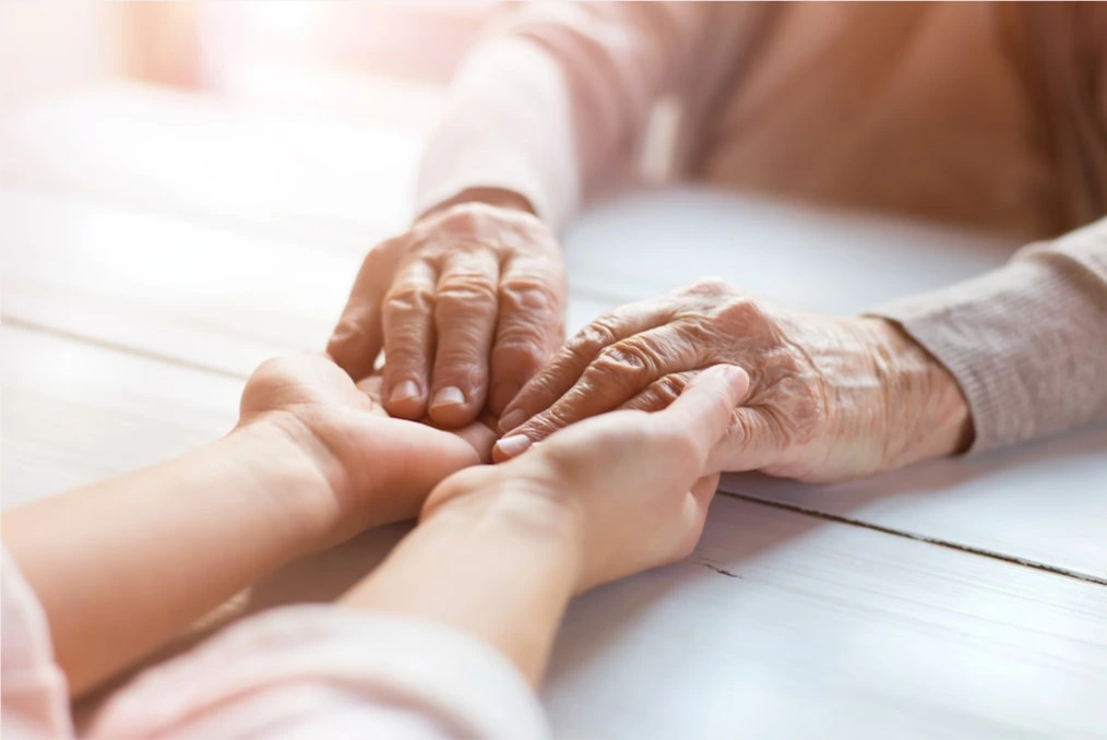 a young person and an older person holding each other's hands