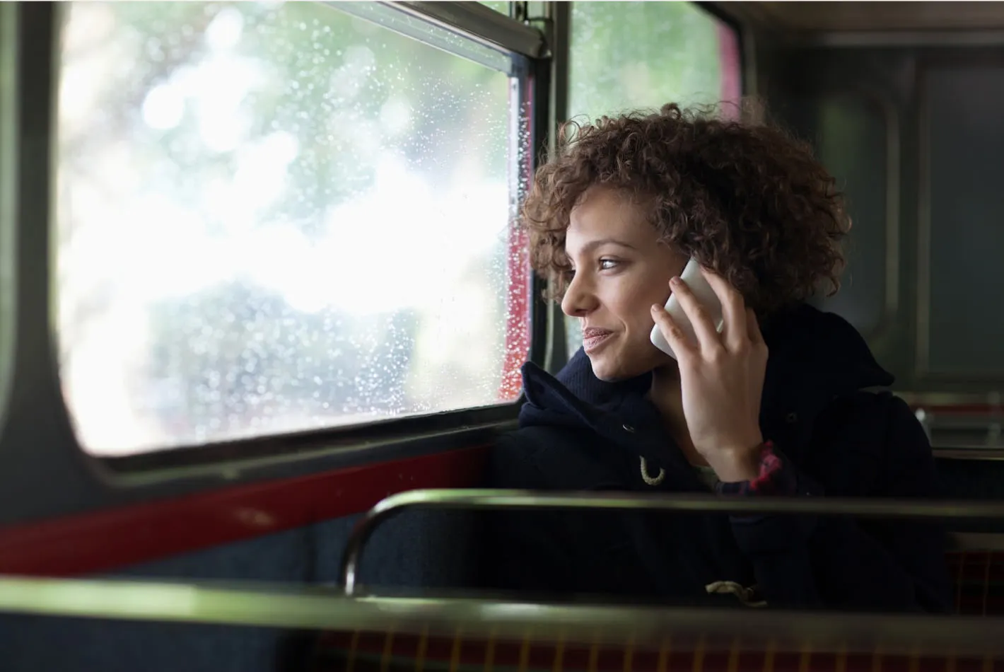 a woman in transit looking out the window while talking on her phone