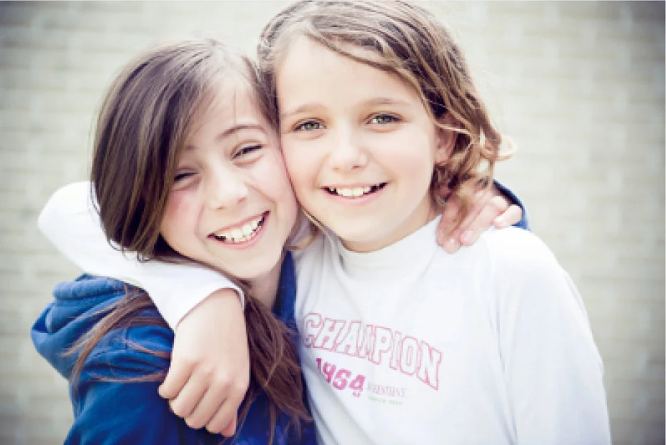2 kids hugging each other smiling