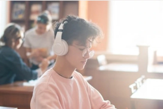 a young man listening to music while studying in a library