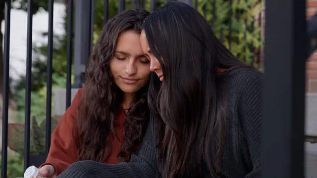 two women sitting together consoling each other