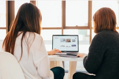 two women discussing with their laptop