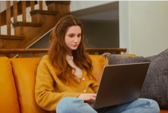 a woman sitting on a couch using her laptop